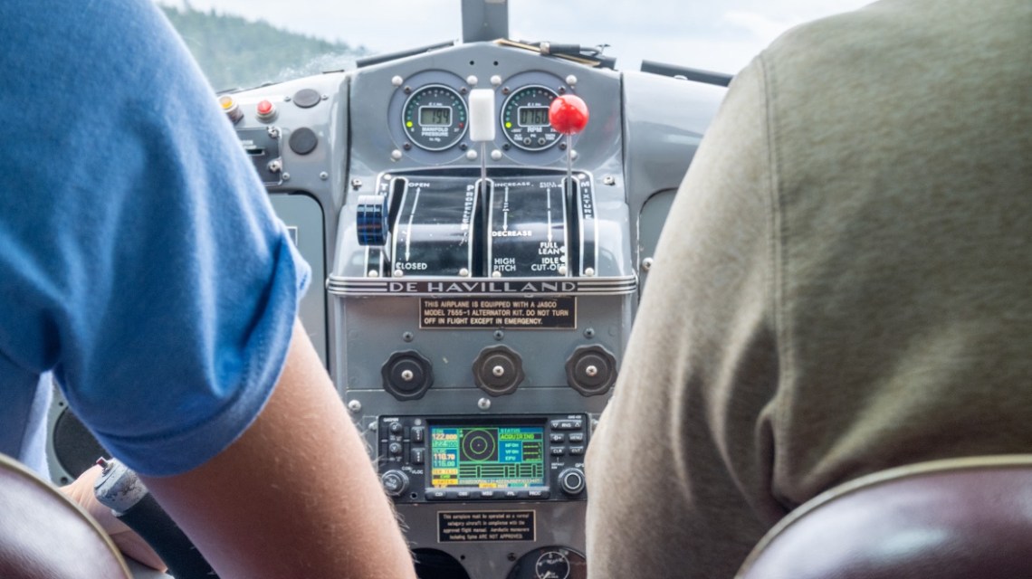 Two pilots in cockpit, viewing instrument panel and controls.